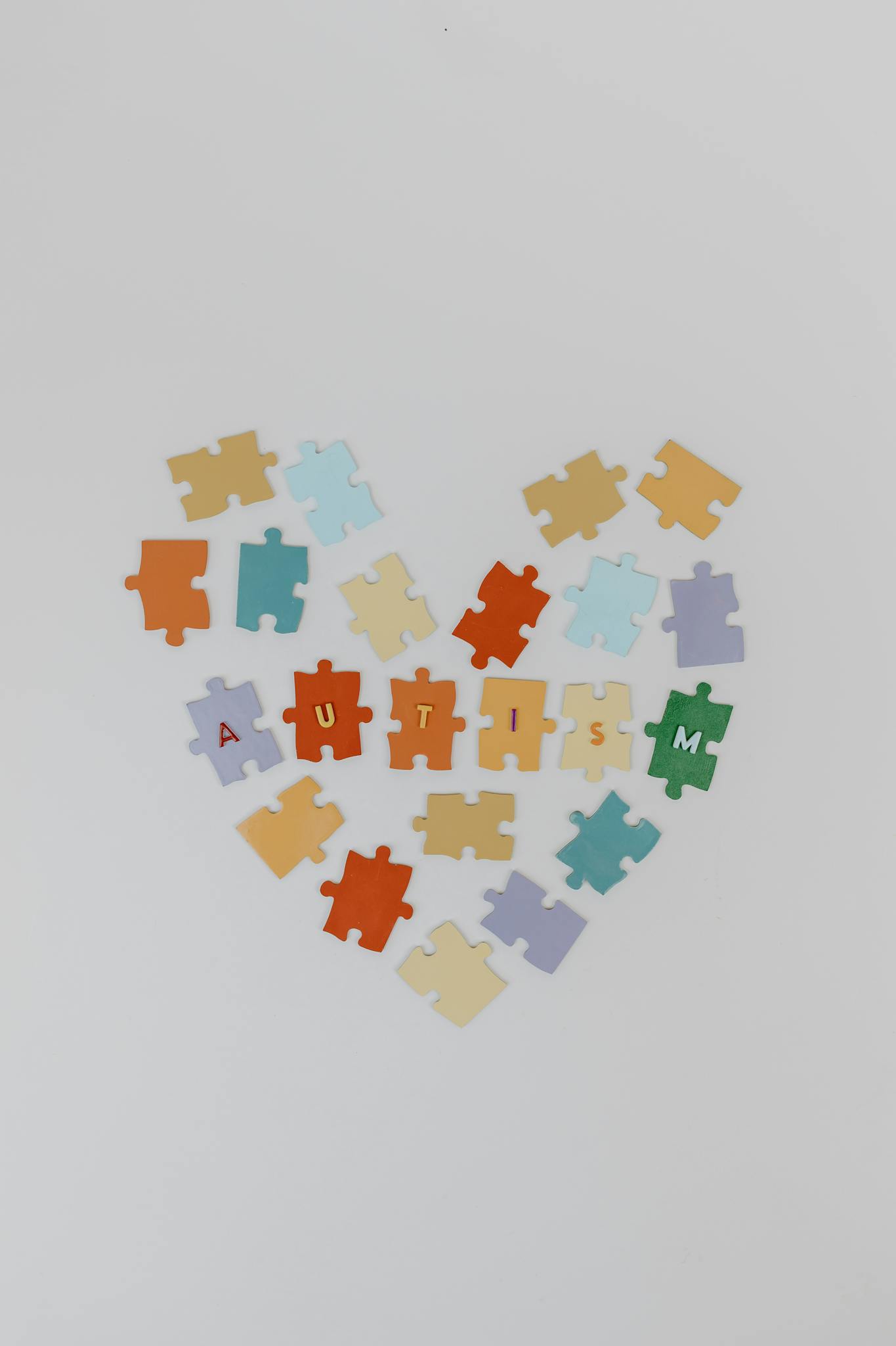 Colorful puzzle pieces form a heart with 'autism' text, symbolizing awareness.